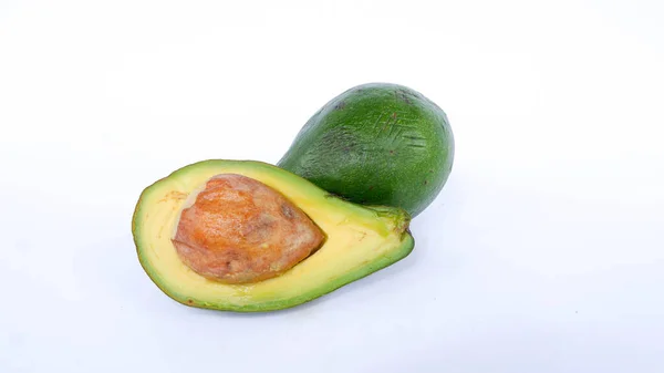 Bölünmüş ve olgunlaşmış yeşil avokado meyvesi. İnsan sağlığı için birçok vitamin içeriyor. Beyaz bir paspasın üzerine yerleştirilmiş.