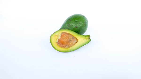 Bölünmüş ve olgunlaşmış yeşil avokado meyvesi. İnsan sağlığı için birçok vitamin içeriyor. Beyaz bir paspasın üzerine yerleştirilmiş.