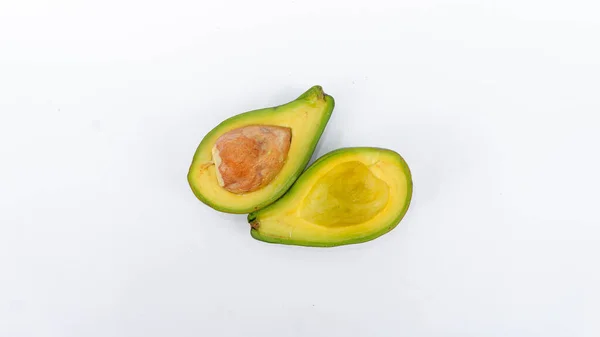 Bölünmüş ve olgunlaşmış yeşil avokado meyvesi. İnsan sağlığı için birçok vitamin içeriyor. Beyaz bir paspasın üzerine yerleştirilmiş.