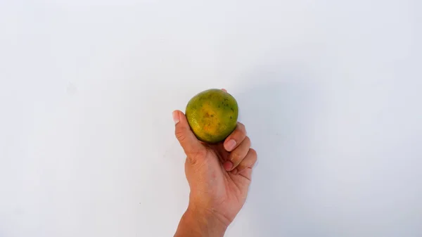 Bir portakalı tutan el yeşildir. Beyaz bir paspasa yapıştırılmış.