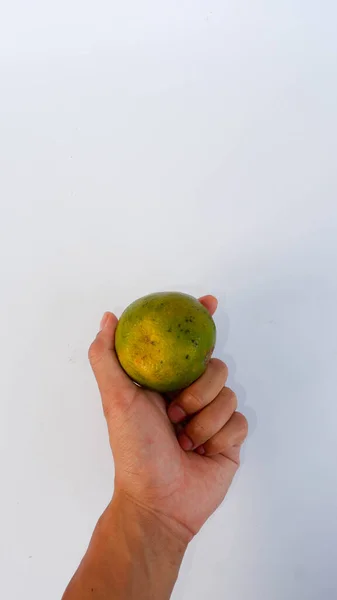 Hand Met Een Hele Sinaasappel Groen Vastgeklemd Een Witte Mat — Stockfoto