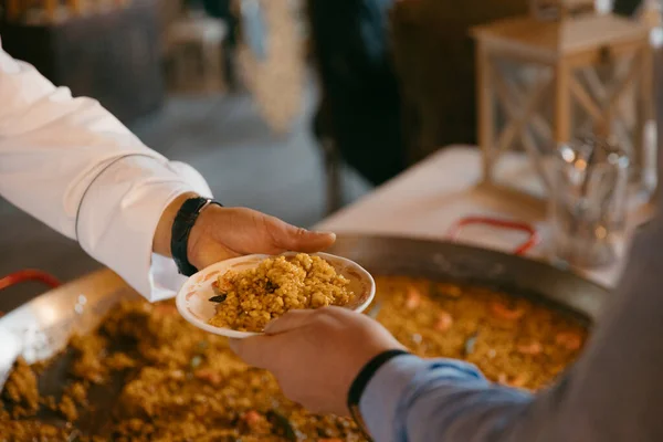 Bir garsonun elinde bir tabak paella teslim edişinin yakın görüntüsü. Yüksek kalite fotoğraf