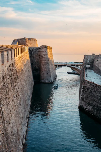 General view of the moat of the Royal Walls of Ceuta at sunset while a ship crosses it. High quality photo