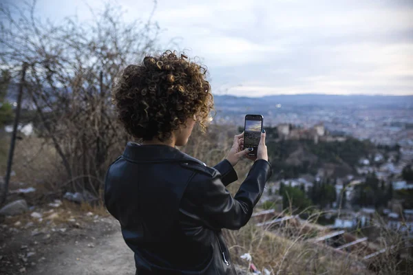 Neşeli Afrikalı kadın gün batımında manzaraya fotoğraf çekmek için akıllı bir telefon tutuyor. Yüksek kalite fotoğraf