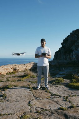 Genç adam deniz üzerinde bir dron çalıştırıyor. Yüksek kalite fotoğraf