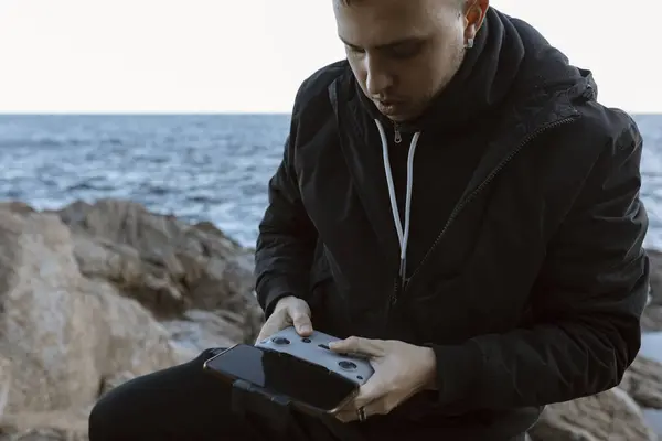 Genç adam deniz üzerinde bir dron çalıştırıyor. Yüksek kalite fotoğraf