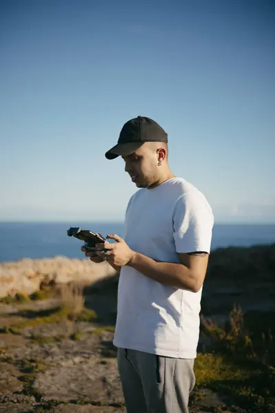 Genç adam deniz üzerinde bir dron çalıştırıyor. Yüksek kalite fotoğraf
