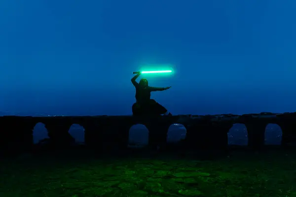 Bulanık saatte elinde ışın kılıcı tutan bir Jedi şövalyesinin genel görüntüsü. Yüksek kalite fotoğraf