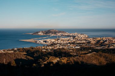 İspanya 'nın Ceuta kentinin Akdeniz' le çevrili panoramik manzarası. Kıyı şehri, tepeler ve liman altın güneş ışığı altında. Seyahat, turizm ve coğrafya konuları için ideal. Yüksek kalite fotoğraf