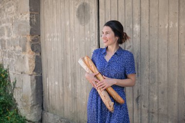 Young pretty woman standing with french baguettes in her hands in the countryside