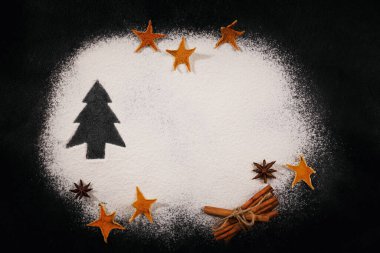 Dağılmış unun üzerine çizilmiş Noel ağacı siyah arka plan, aksesuarlar ve malzemeler. Mutlu Noeller ve mutlu yıllar 2023. Üst görünüm