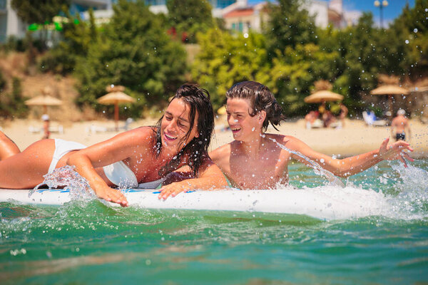 Mom with her teen son lying on a swimming board. Happy european family having fun floating on a swim board in the sea on a hot summer day