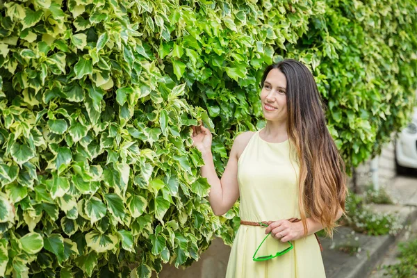 Žena Obklopená Bujnými Zelenými Rostlinami Dotýkající Listí Běloška Zdi Oblečená — Stock fotografie
