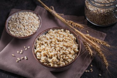 Koyu ahşap arka planda buğday kulaklı kabuklu arpa taneleri. Sağlıklı ve diyet gıda konsepti