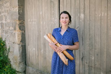 Young pretty woman standing with french baguettes in her hands in the countryside