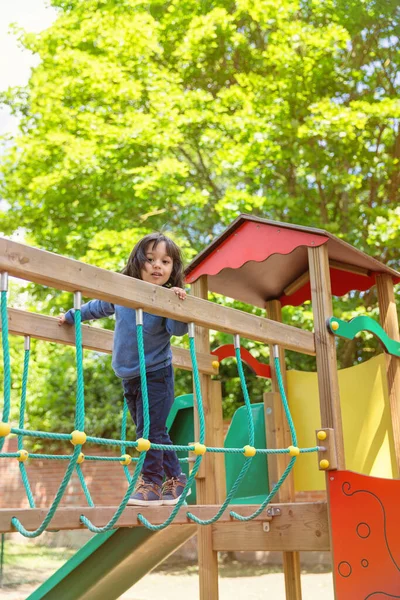 stock image Handsome active little boy having fun while playing and climbing on the outdoor playground. Kids play on school or kindergarten colorful yard. Healthy summer activity for children.