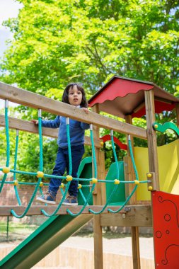 Yakışıklı, hareketli küçük çocuk dışarıda oyun oynarken ve tırmanırken eğleniyor. Çocuklar okulda ya da anaokulunun renkli bahçesinde oynarlar. Çocuklar için sağlıklı yaz etkinliği.