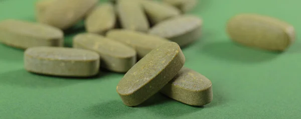 Herbal and Vitamin green pills healthy food freely laid on green background for healthy eating in daily life. Macro close up