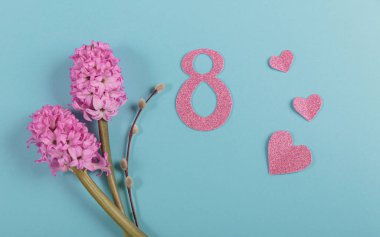 March eight Womens Day card from spring hyacinth flowers and number 8 with paper hearts top view. Minimal greeting card for International Women Day on blue background