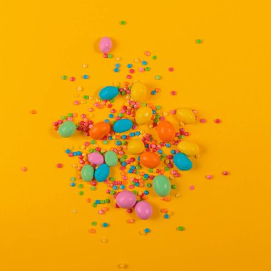 Delicious chocolate colorful coated candy on yellow background. Decoration for cake and bakery. Happy sweet easter concept. Top view, flat lay with free space for text