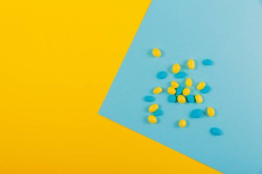 Delicious chocolate colorful coated candy on yellow blue background. Decoration for cake and bakery. Top view, flat lay with free space for text