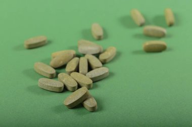 Herbal and Vitamin green pills healthy food freely laid on green background for healthy eating in daily life