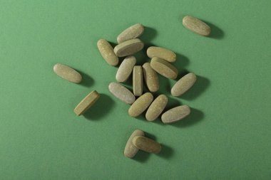 Herbal and Vitamin green pills healthy food freely laid on green background for healthy eating in daily life