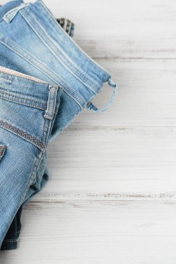 Beyaz arka planda bir yığın kot pantolon. İkinci el giyim mağazası. Dairesel moda, çevre dostu sürdürülebilir alışveriş, ikinci el mağazaları konsepti. Metin için boş kopyalama alanı