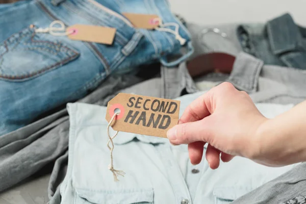 İkinci el mağazasının rafındaki kadın kıyafetleri. Kadınlar el sanatları el yazısı ve ikinci el yazısıyla el yazısı tutarlar. Dairesel moda, çevre dostu alışveriş, ikinci el mağazalar konsepti