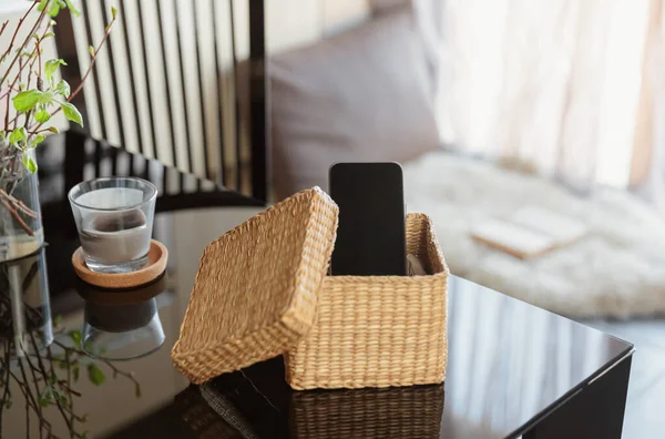 Smartphone is in separate wicker box on table. Refuse to use digital gadgets at home in favor of live communication with family. Digital detox and technology dependance concept