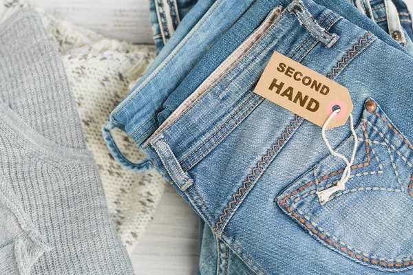 Kot pantolon yığını ve üzerinde ikinci el yazılar var. İkinci el giyim mağazası. Dairesel moda, çevre dostu sürdürülebilir alışveriş, ikinci el mağazaları konsepti. Kadın kıyafetinden daha iyi görünüyor.