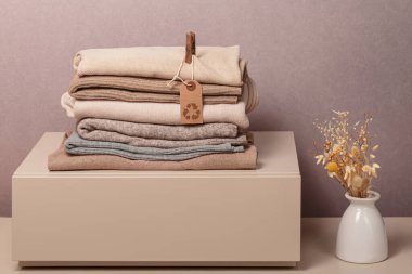 Giysi yığını, kullanılmış kostüm ve üzerinde yuvarlak ekonomi logosu olan etiket. Yeniden kullanım, geri dönüşüm malzemeleri, moda atıklarının azaltılması, ikinci el giyim fikri. Dairesel moda, sıfır atık kavramı