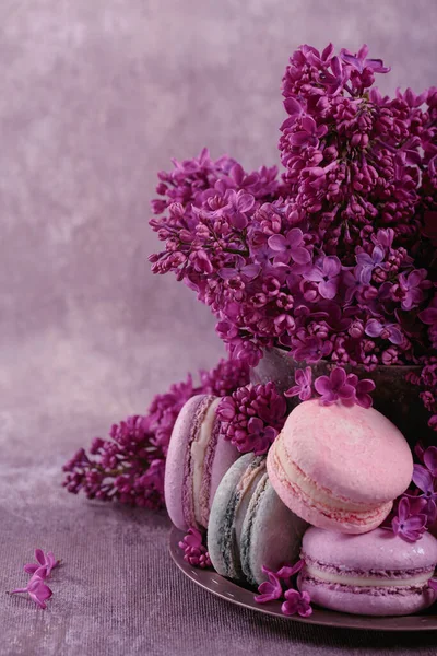 Süße Pastellfarbene Französische Makronen Und Fliederfarbene Blumen Auf Grauem Hintergrund — Stockfoto
