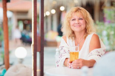 Portrait of a young woman drinking beer on the terrace of a beach cafe on a summer sunny day