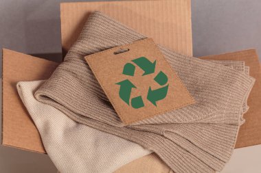 Yeniden kullanım için kullanılmış gardırop ve yuvarlak ekonomi logosu olan kart dolu karton kutu. Yeniden kullanım, geri dönüşüm malzemeleri, moda atıklarının azaltılması, ikinci el giyim fikri. Dairesel moda, sıfır atık kavramı