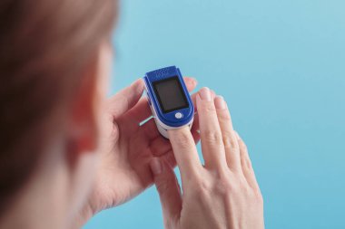 Parmağındaki nabız oksimetresinden çıkan kan oksijeni için kendini test eden tanımlanamayan bir kadın. Sağlık hizmetleri izleme konsepti
