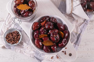 Marinated plums with spices in glass jar on the kitchen table. Homemade canning. Vegetable snack for winter.