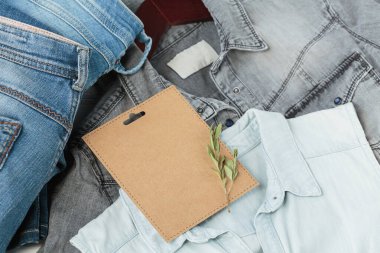 Askıda kot pantolon ve kotlu tişörtler ve boş el işi kartlarıyla sürdürülebilir bir hayat. İkinci el kıyafet fikri. Dairesel moda, bağış, bağış konsepti.