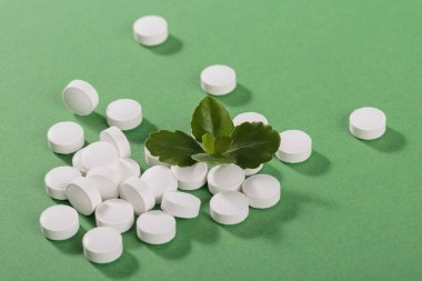 Herbal and Vitamin white pills healthy food freely laid on green background for healthy eating in daily life