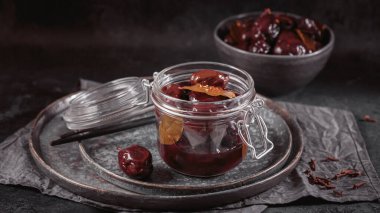 Bowl of pickled plums with spices on rustic wooden background. Clean eating, vegetarian food concept