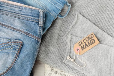 Kot pantolon yığını ve üzerinde ikinci el yazılar var. İkinci el giyim mağazası. Dairesel moda, çevre dostu sürdürülebilir alışveriş, ikinci el mağazaları konsepti. Kadın kıyafetinden daha iyi görünüyor.