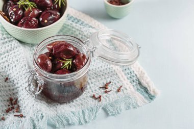 Bowl of pickled plums with spices on rustic wooden background. Clean eating, vegetarian food concept