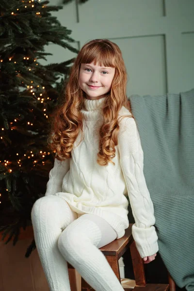 家の居心地の良いリビングルームでクリスマスツリーに座って笑顔の幸せな若い女の子 幸せな冬の休日のコンセプト — ストック写真