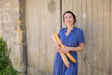 Young pretty woman standing with french baguettes in her hands in the countryside