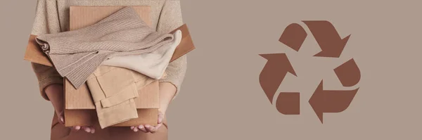 Giysi dolabı kullanılmış ve bej arka planda dairesel ekonomi logosu vermeye hazır bir kadın elinde karton kutu tutuyor. Dairesel moda, kıyafet geri dönüşümü, çevre dostu sürdürülebilir alışveriş kavramı