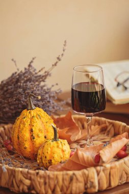 Balkabağı ve kuru yapraklarla süslenmiş ahşap masada bir bardak kırmızı şarap. Şükran Günü için sonbahar kompozisyonu. Sonbahar havası
