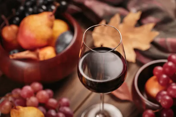 濃い木の背景にフルーツを添えた豊かな赤ワインのグラス 秋はまだ素朴なスタイルでワイン ブドウ 乾燥した葉で生きています セーター気象コンセプト — ストック写真