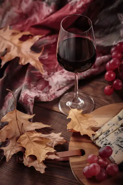 秋天的舒适生活与一杯红酒 奶酪盘 季节性的水果和干燥的叶子 乡村风格在黑暗的木制背景 毛衣天气概念 — 图库照片