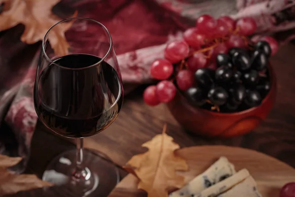 赤ワインのグラスは 濃い木の背景に青いチーズを添えました ロマンチックなスタイルのワインとチーズのプラッター 果物と乾燥した葉と秋のピクニック — ストック写真