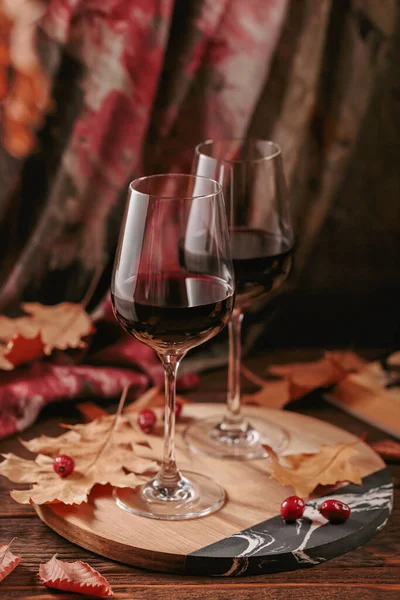 秋の居心地はまだ赤ワインのメガネ 乾燥した葉が濃い木の背景に素朴なスタイルで生きています ワインテイスティング セーター気象コンセプト — ストック写真